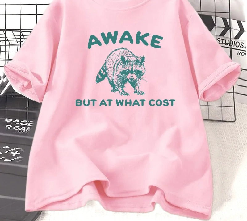 Pink cotton tee printed with a teal engraved raccoon and the words awake but at what cost