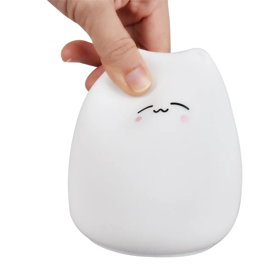 A finger pressing the top of the soft silicone cat