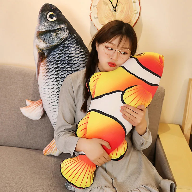 A person hugging the clownfish pillow with the grass carp behind it - one fish per order