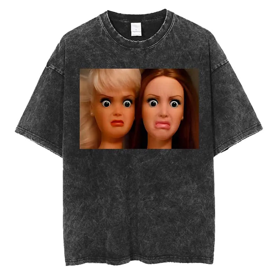 Washed charcoal tee printed with a photograph of two fashion doll heads side by side, both wide eyed and grimacing