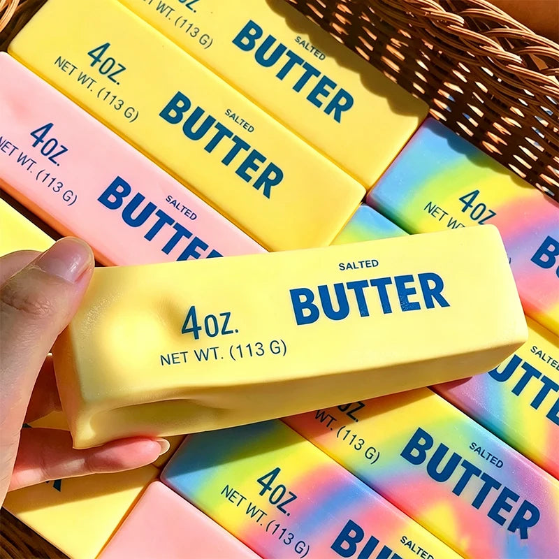 A yellow squishy butter stick squeezed in one hand above a pile of pink, yellow and rainbow blocks
