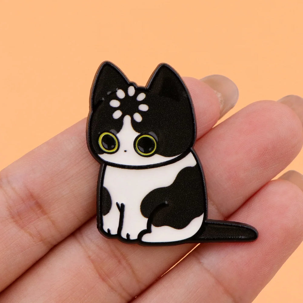 Black and white tuxedo cat magnet held in a hand to show its size