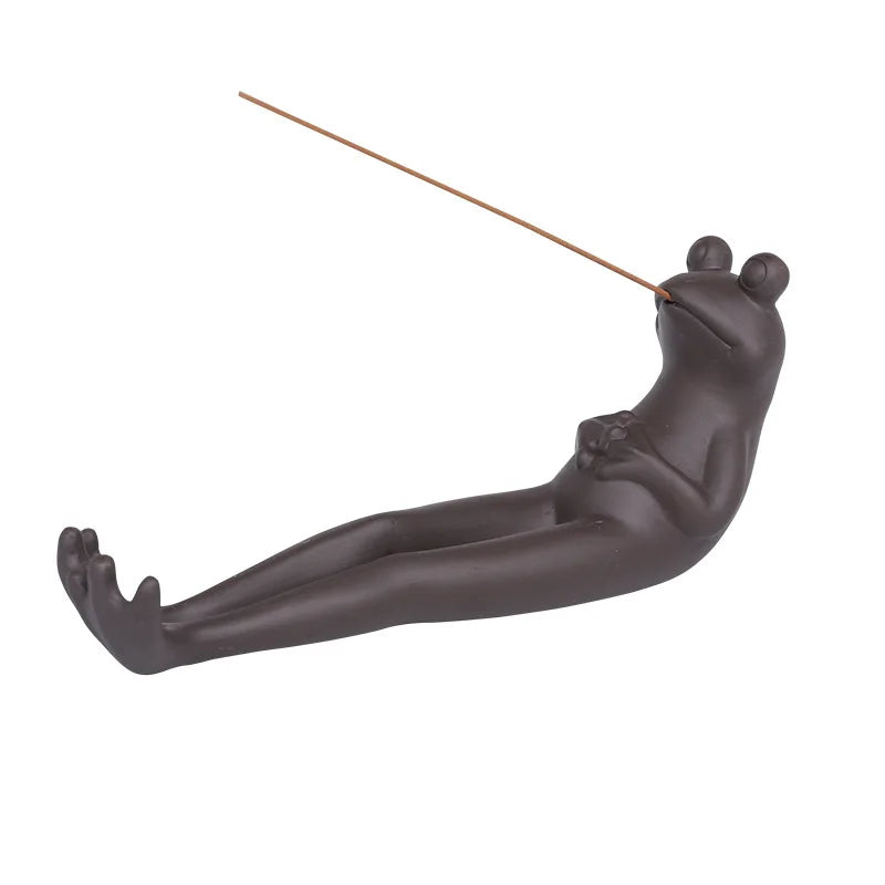 The frog holder on a plain background with an incense stick in place