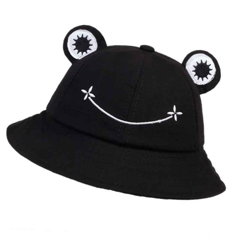 Black cotton bucket hat with applique frog eyes and a white embroidered smile