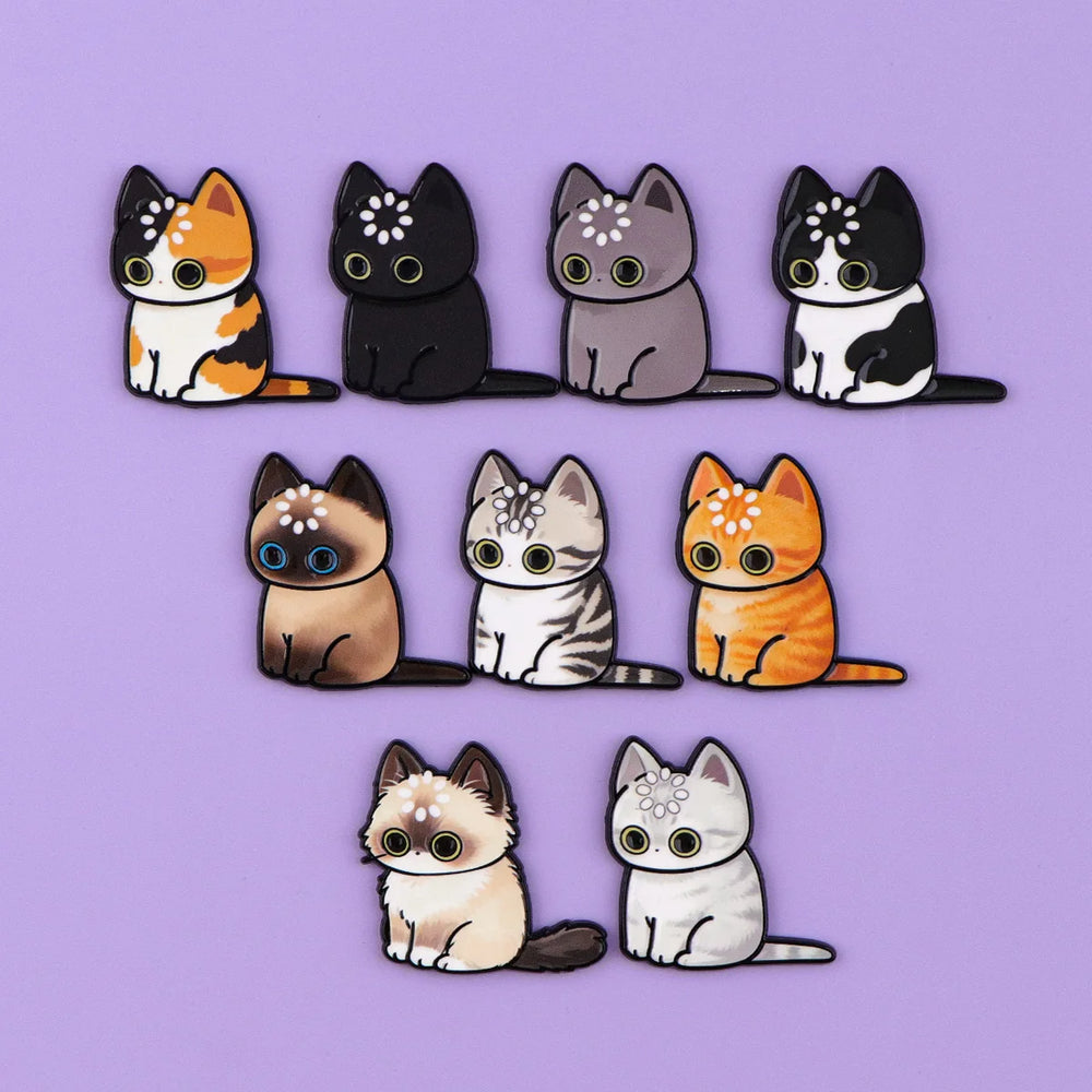 All nine cat magnets arranged on a lilac background, each with a ring of dots on its head