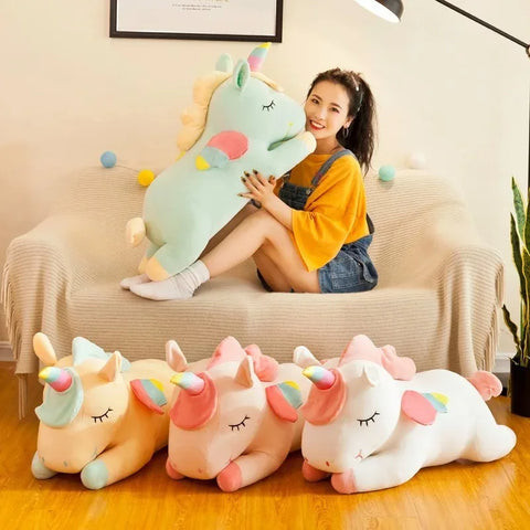 Five of the unicorns lined up on a sofa and floor while someone hugs the mint green one - one unicorn per order, the room is staging