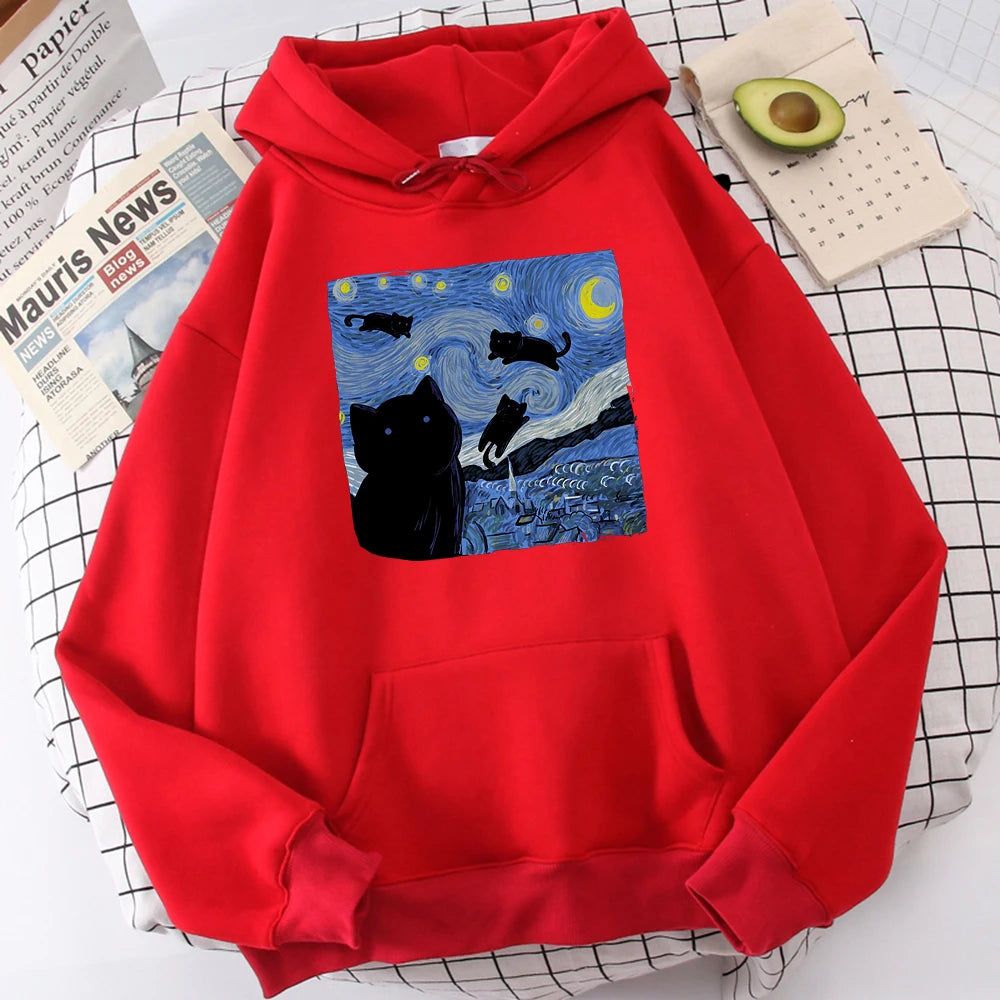 Red fleece pullover hoodie with a large front print of a swirling starry night sky, a crescent moon and black cats over a village