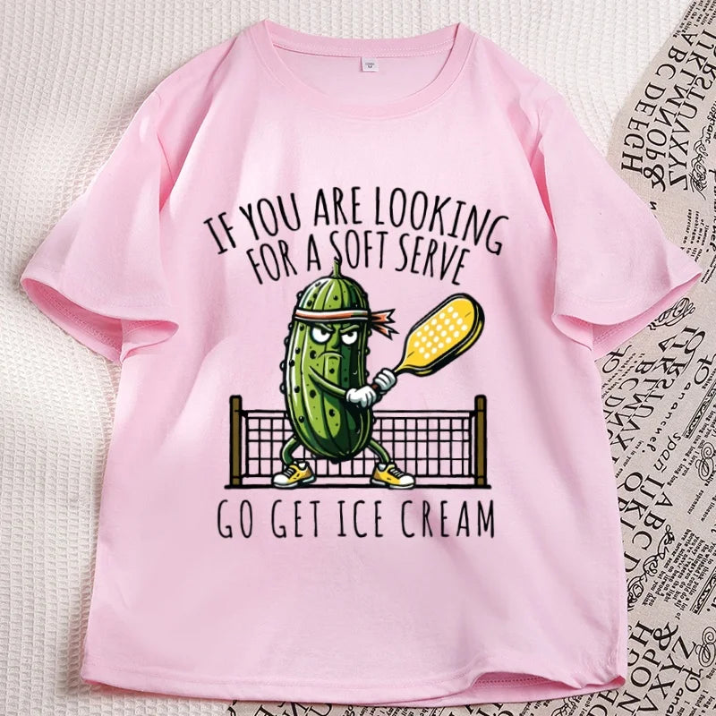 Pink pickleball tee laid flat, cartoon pickle with a paddle printed on the chest