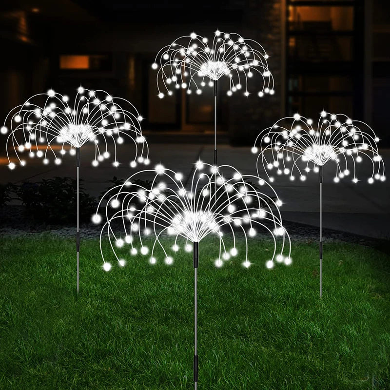 Cool white solar firework stake lights on a lawn at night