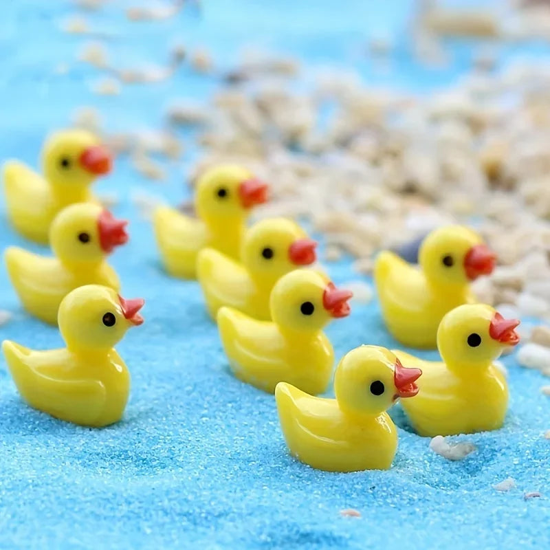 A row of tiny yellow resin ducks standing on blue sand
