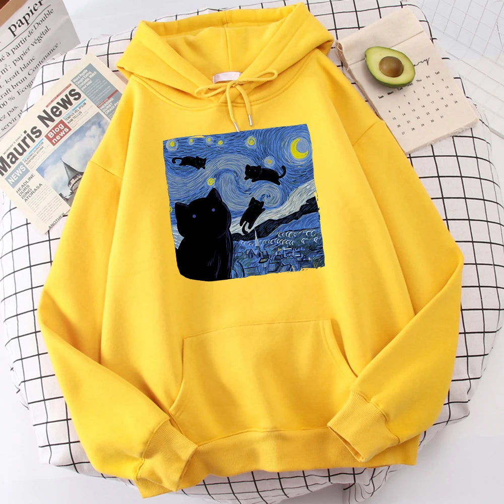 Yellow fleece pullover hoodie with a large front print of a swirling starry night sky, a crescent moon and black cats over a village
