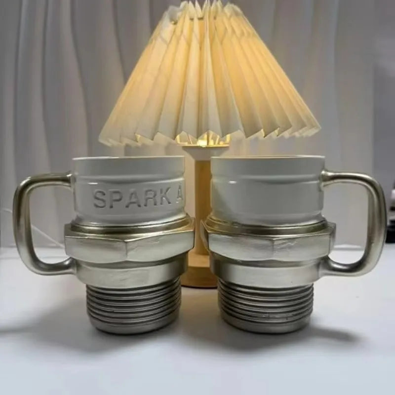 Two of the mugs standing beside a pleated table lamp - one mug is included per order and the lamp is not included