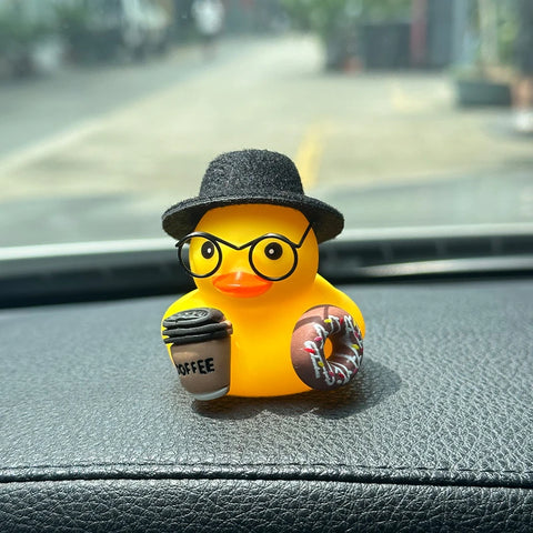 Black Hat: yellow rubber duck in a black felt hat and round glasses, holding a coffee cup and a pink donut