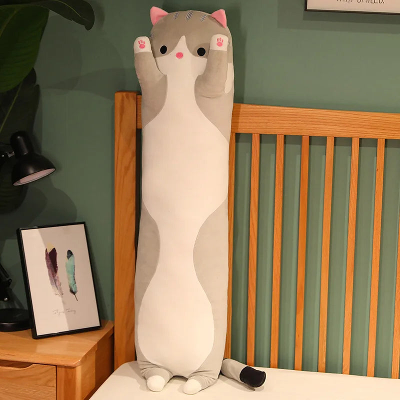 Grey long cat body pillow standing upright against a bed frame