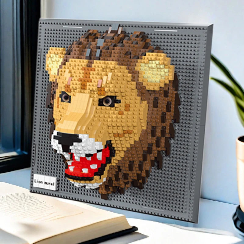 Brick built lion head on a grey studded panel, propped on a desk beside an open book and a plant