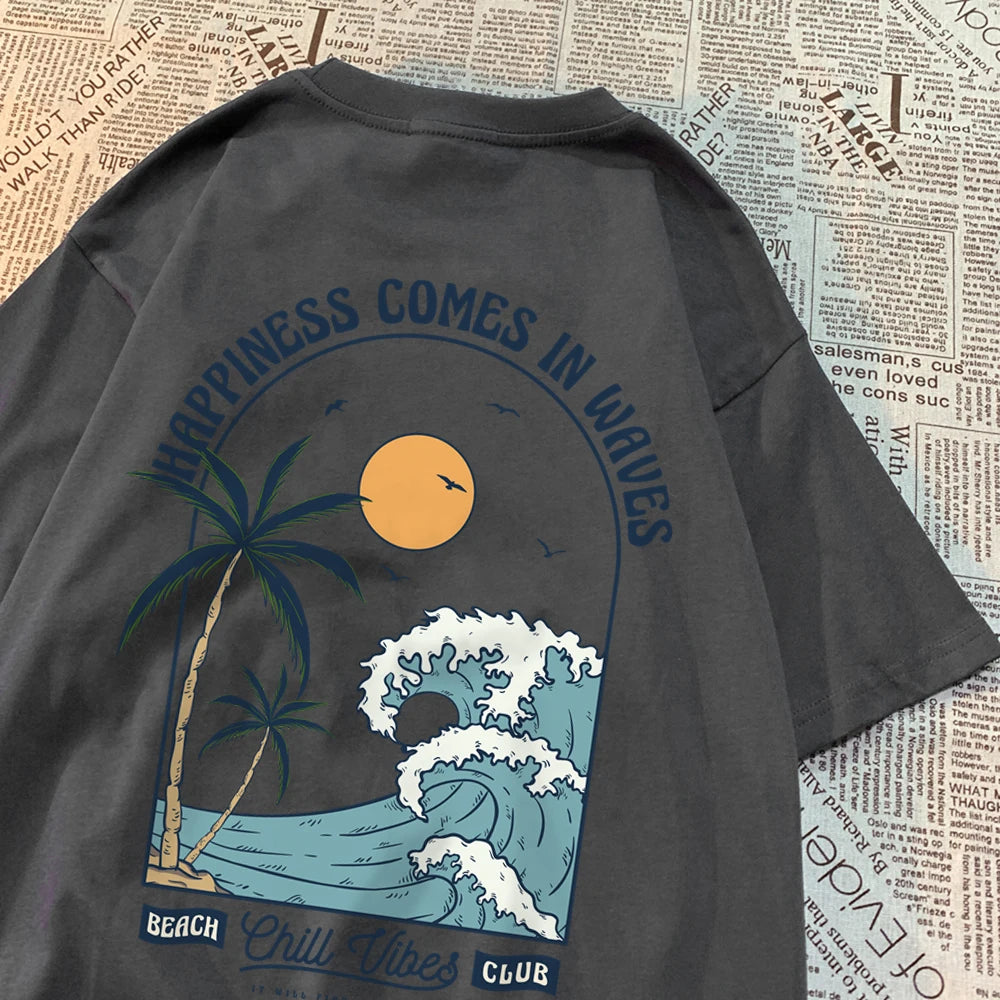 Dark grey cotton tee with a large back print of a breaking wave, palm trees and a low sun, under the arched words Happiness Comes In Waves
