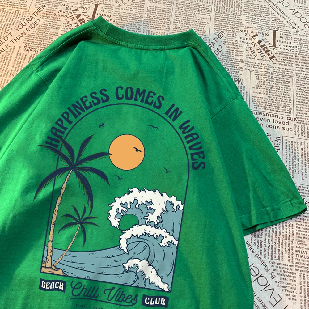 Green cotton tee with a large back print of a breaking wave, palm trees and a low sun, under the arched words Happiness Comes In Waves