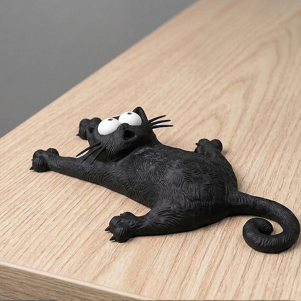 The same cat figure lying on its back on a wooden surface