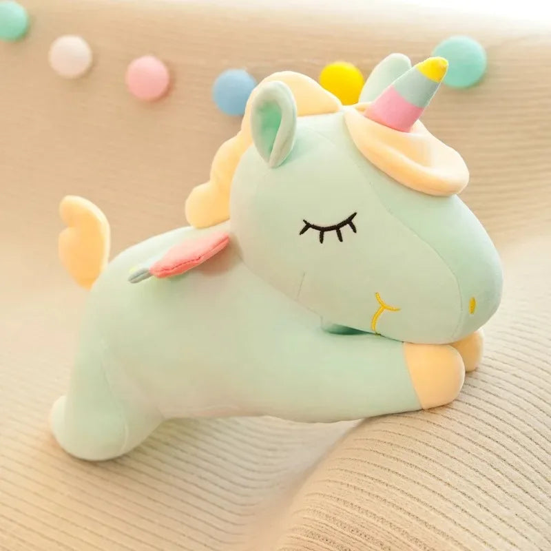 The mint green unicorn lying down, cream mane and rainbow-striped horn