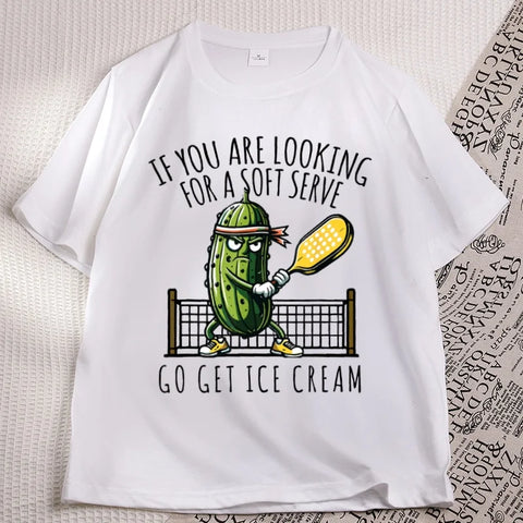 White pickleball tee laid flat, cartoon pickle with a paddle printed on the chest