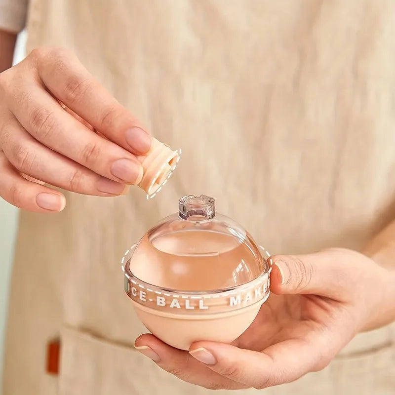 Hands lifting the screw cap off a peach ice ball mold held in an open palm