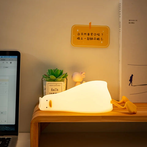 Silicone duck night lamp glowing warm on a wooden desk