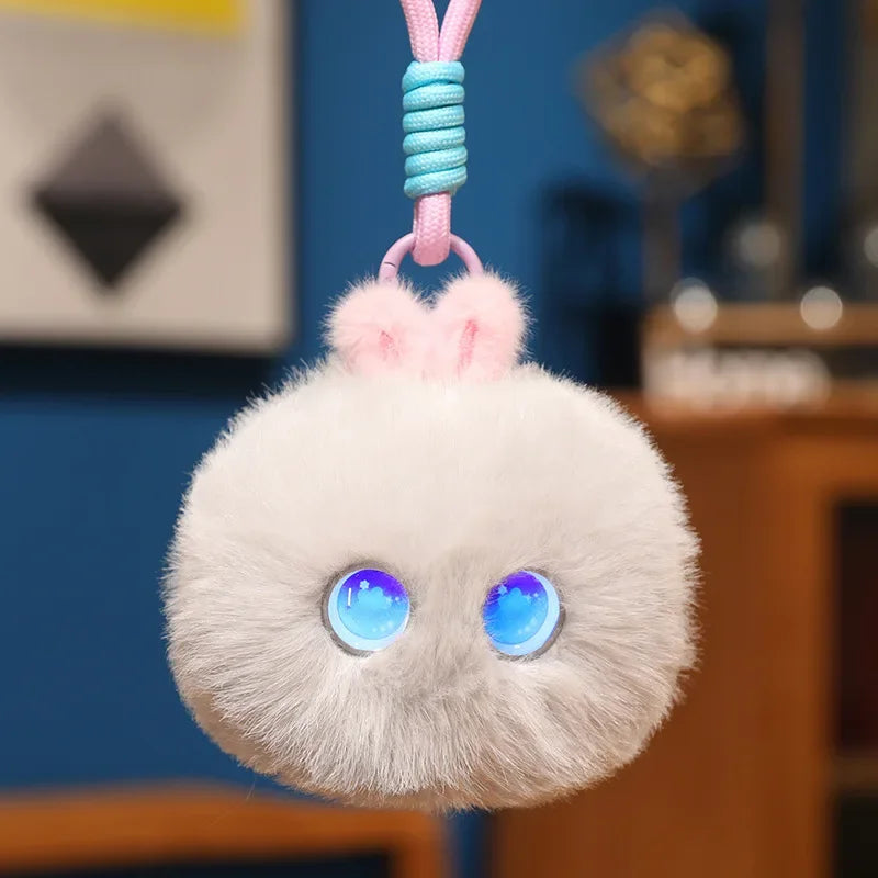 Pale grey fluffy pom-pom charm with round blue light-up eyes, hanging from its cord