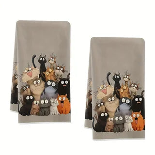 Two matching warm grey kitchen towels laid side by side, each printed with a crowd of cartoon cats