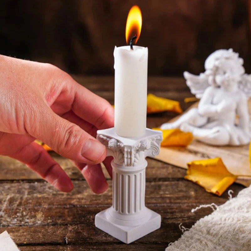 A hand lighting a taper candle set in the white column holder; candle not included