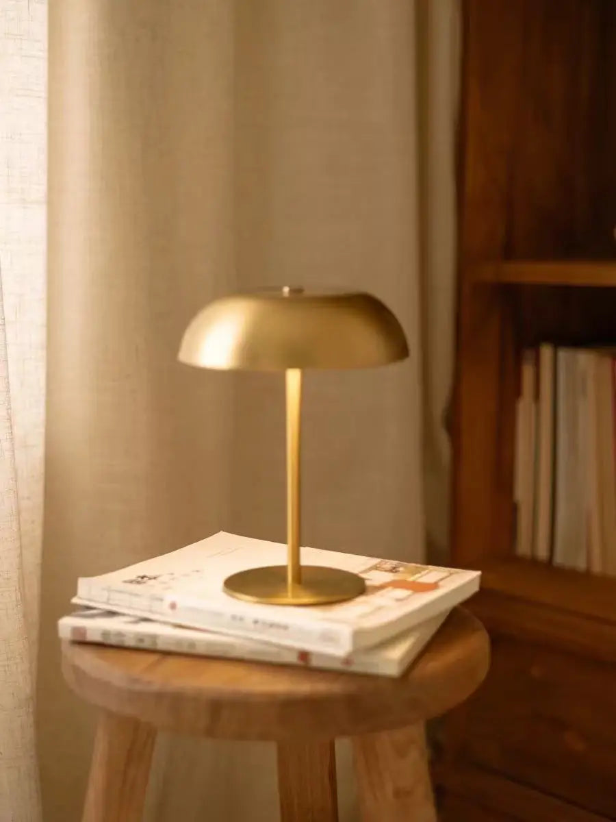 The gold lamp lit warm beside a stack of books
