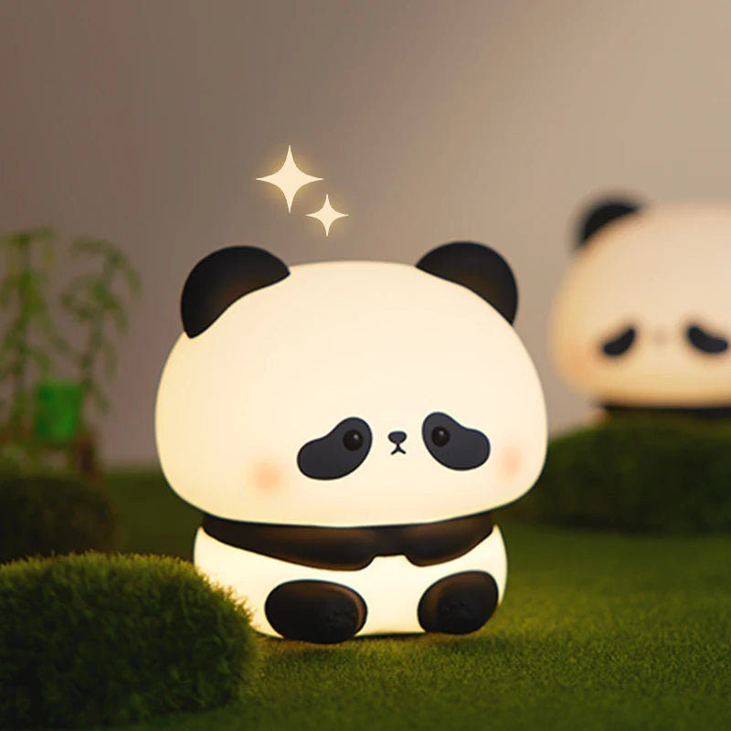 The sitting panda night light glowing warm white on moss beside a bamboo shoot, a second one blurred behind it