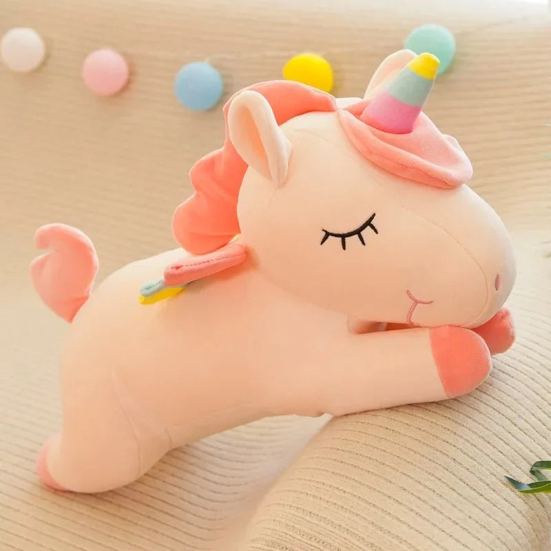 The pink unicorn lying down, pink mane and rainbow-striped horn, eyes stitched closed