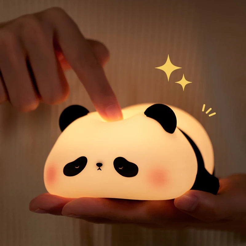 A fingertip pressing down on the top of the panda light head, denting the soft shell, while the other hand holds it from below