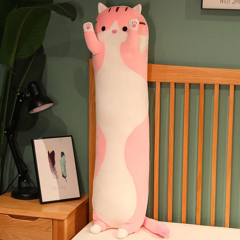 Pink long cat body pillow standing upright against a bed frame