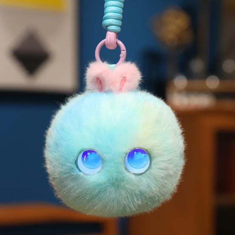 Mint and pale yellow fluffy pom-pom charm with round blue light-up eyes, hanging from its cord