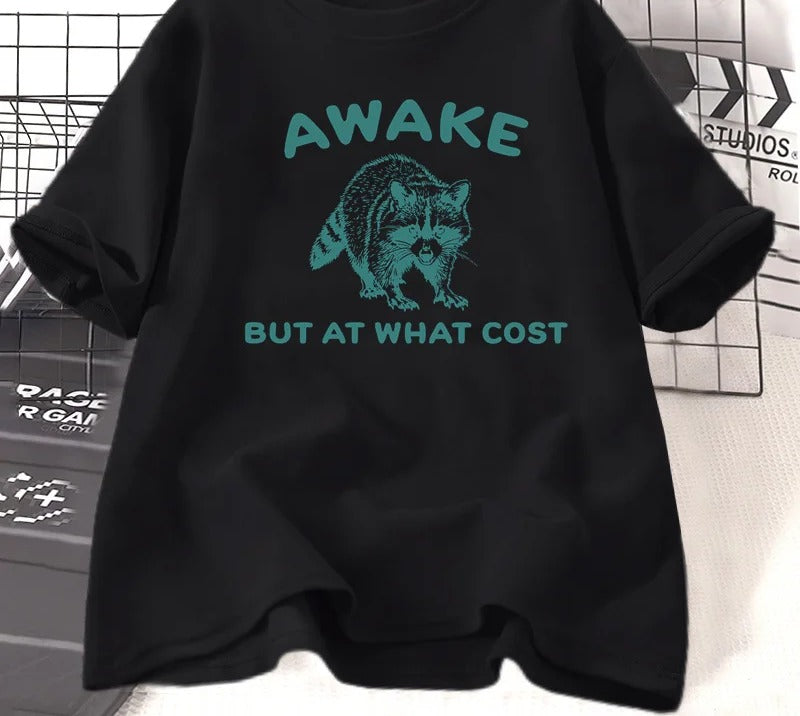 Black cotton tee printed with a teal engraved raccoon and the words awake but at what cost