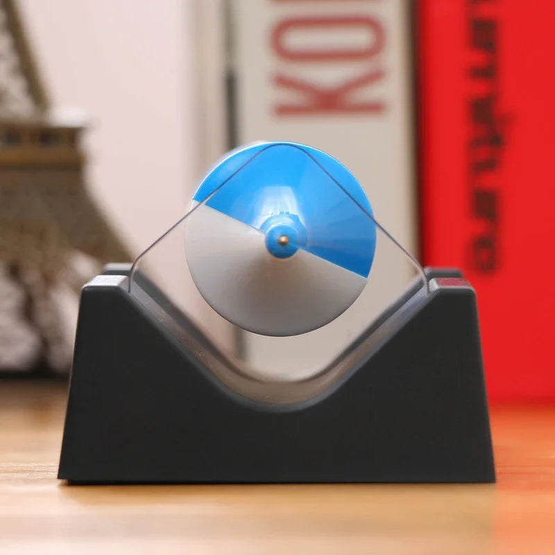 Blue and white top spinning above the magnetic cradle on its black base
