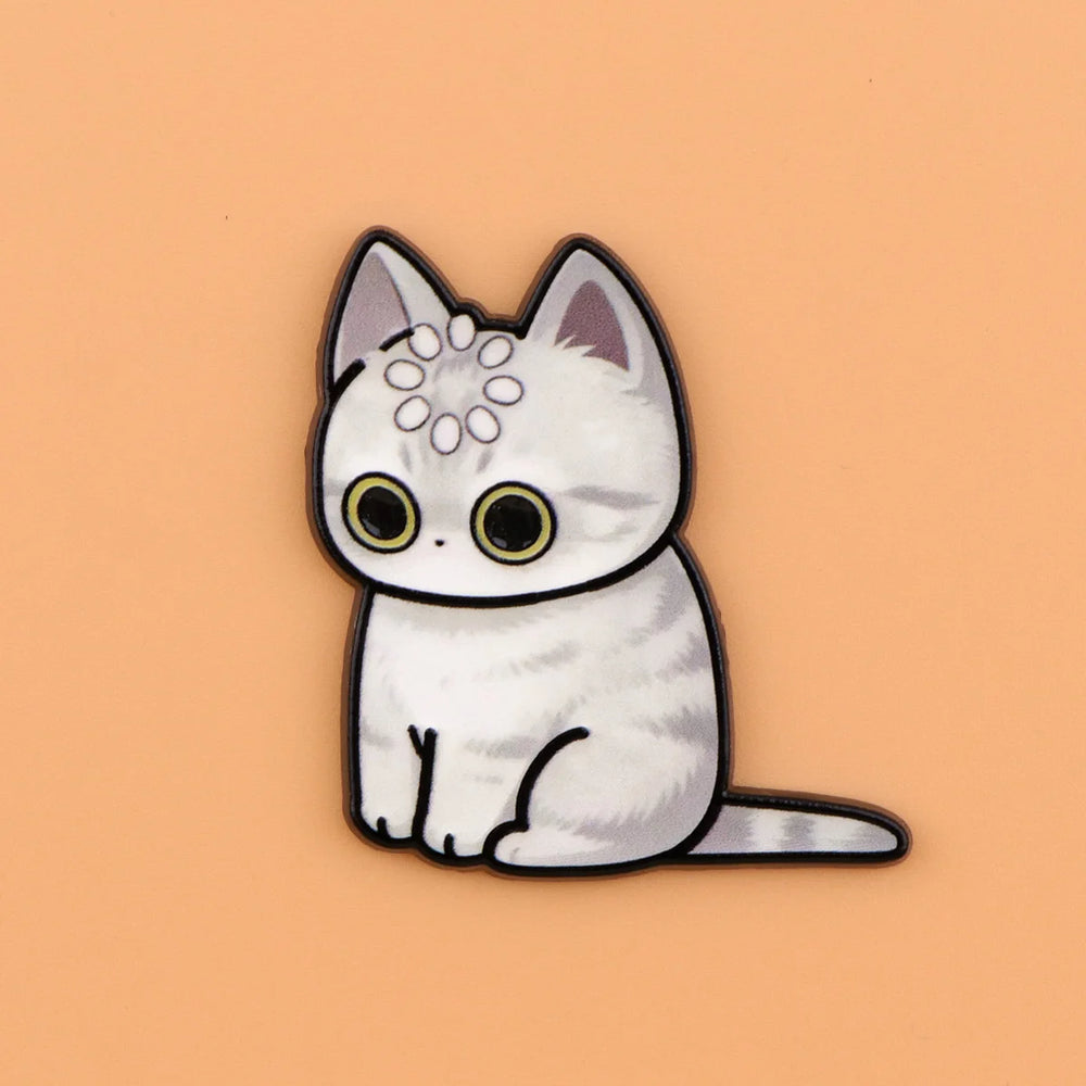 Snow white cat magnet with faint silver markings and a ring of dots on its head