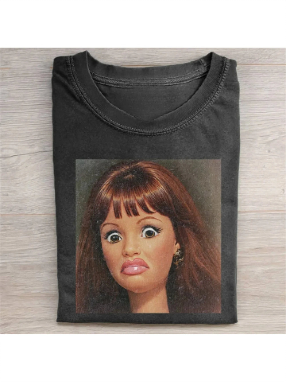 Washed black tee printed with a photograph of a brunette fashion doll with a fringe, mid-grimace