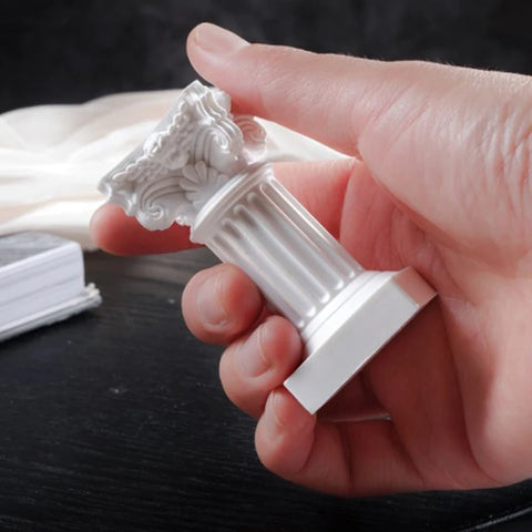A hand holding the small white resin column candle holder