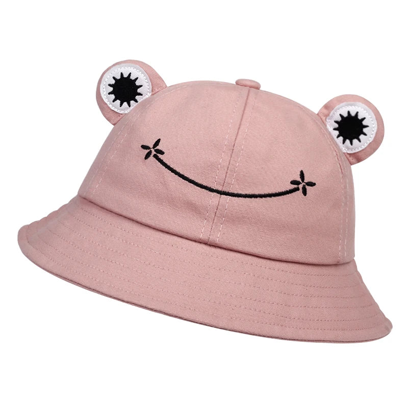Pink cotton bucket hat with applique frog eyes and an embroidered smile