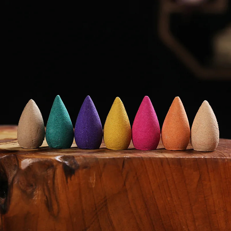 A row of backflow incense cones in different colours on a wooden block