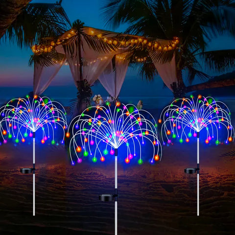 Multicolour solar firework stake lights beside a palm-shaded terrace at dusk