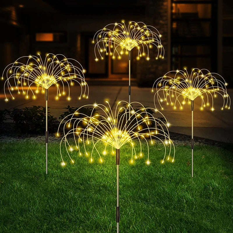 Warm white solar firework stake lights on a lawn at night