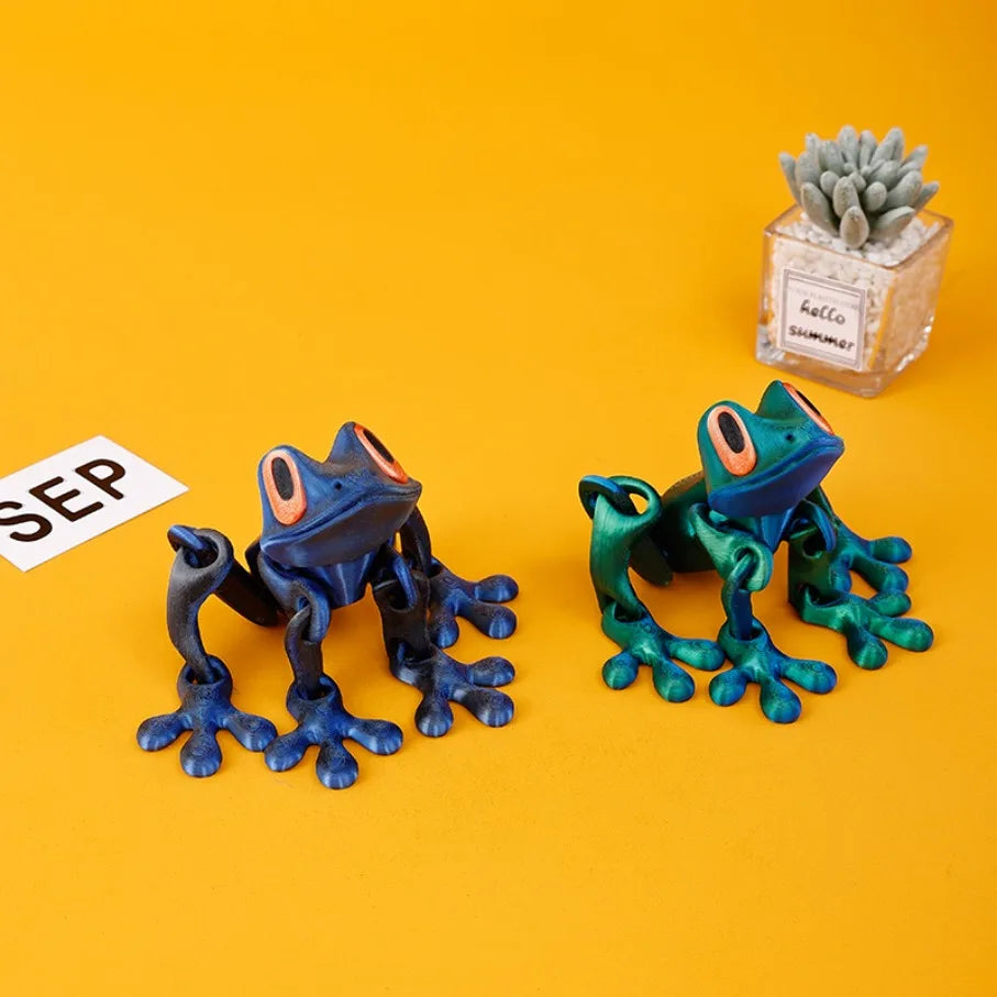 Two frogs beside a small plant and a paper note on an orange background