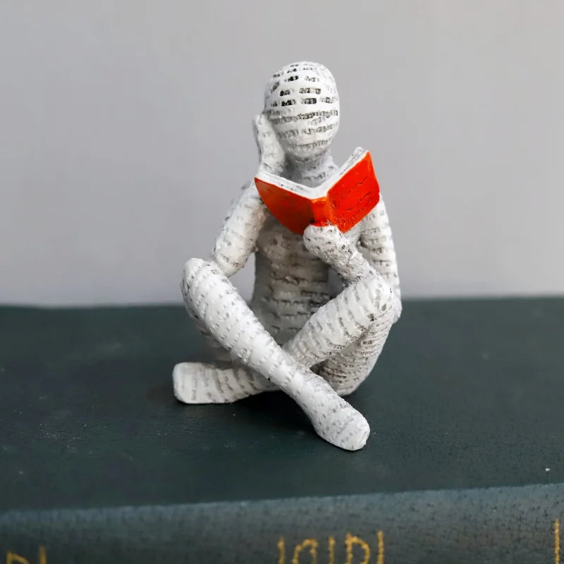 The cross-legged figure reading on top of a green hardback