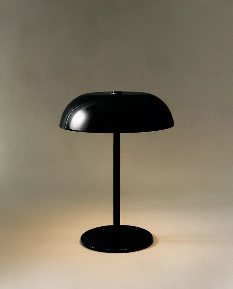Black lamp seen from the side, showing the stem and round base