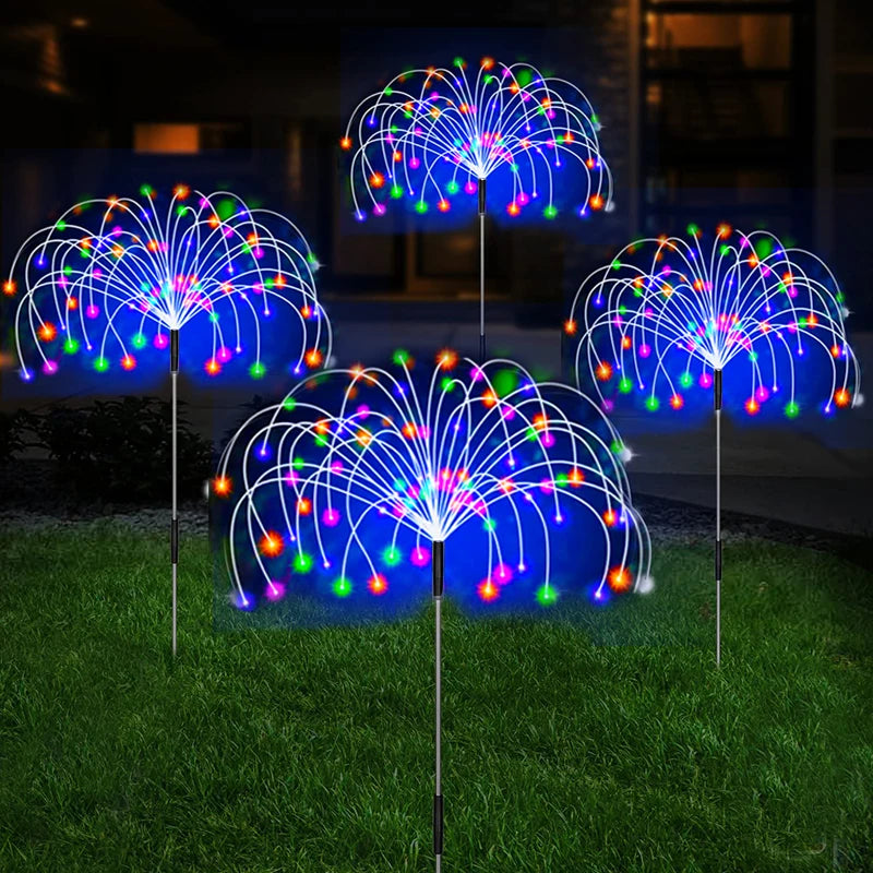 Multicolour solar firework stake lights on a lawn at night