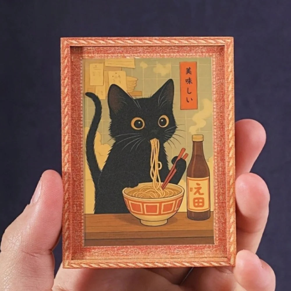The framed cat magnet held between finger and thumb, showing how small it is
