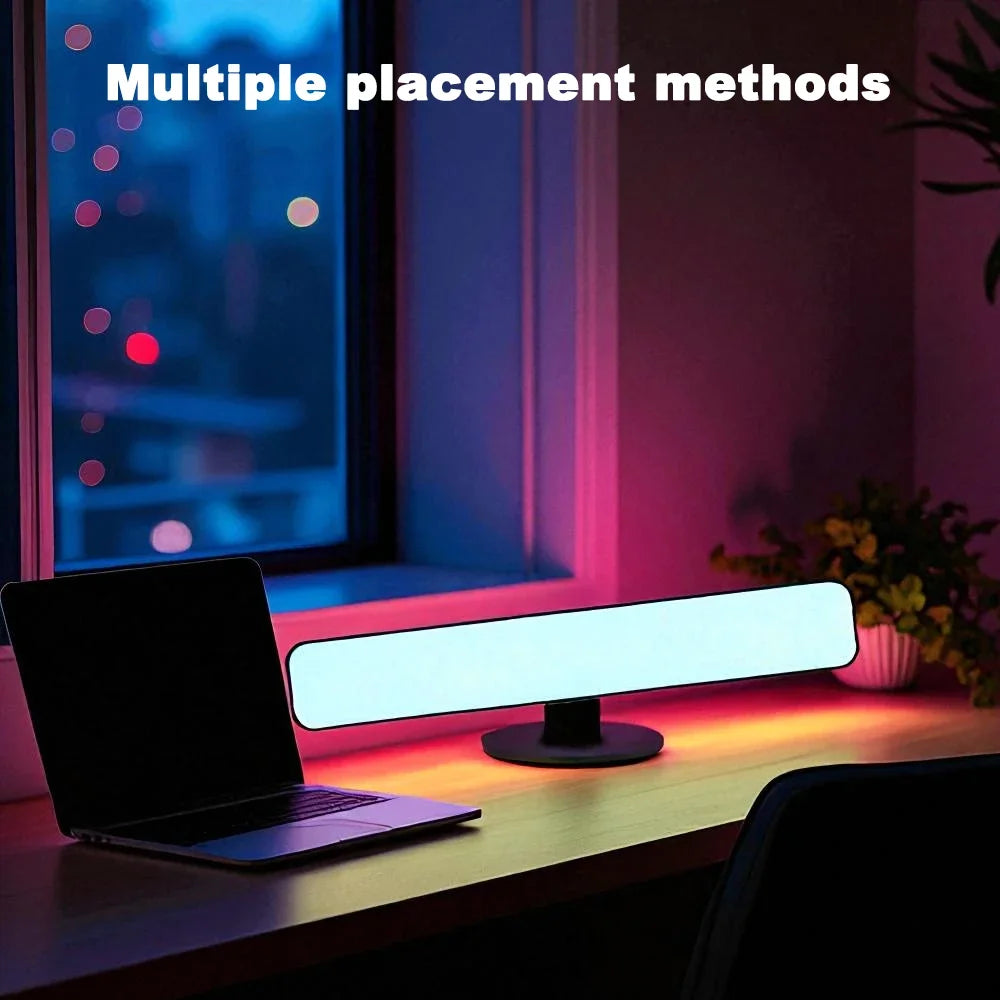 A single light bar lying flat behind a laptop, throwing pink and orange light across a dark room